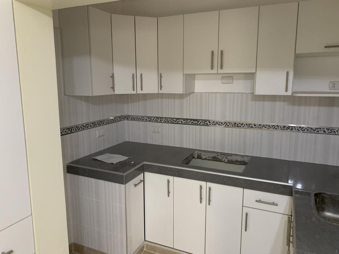 After: a bright kitchen with new white cabinets, grey counters and a tiled backsplash