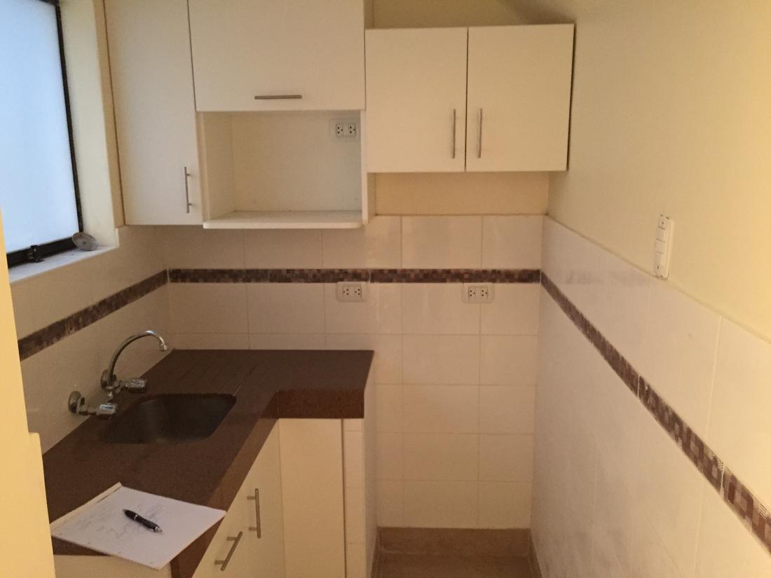After: a clean kitchen with new cabinets, a dark counter and fresh tiles
