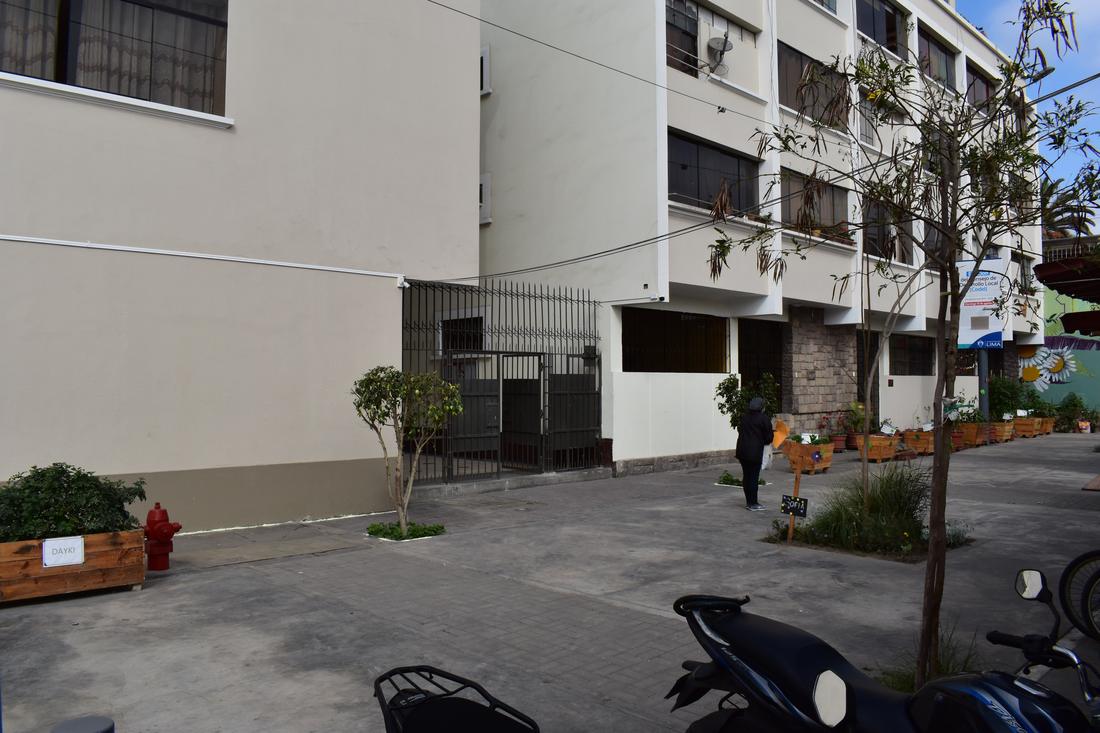 After: the same gate with fresh paint, young trees and planters along a clean walkway