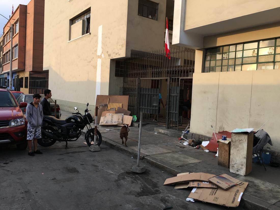 Before: a building gate with cardboard and rubbish piled on the pavement and a loose dog