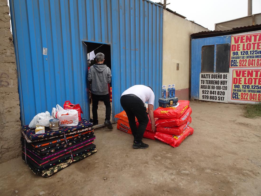 Food sacks and dog beds stacked outside a blue metal gate